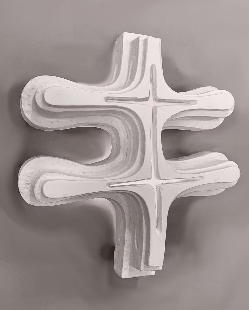 A cross shaped object is shown in black and white.