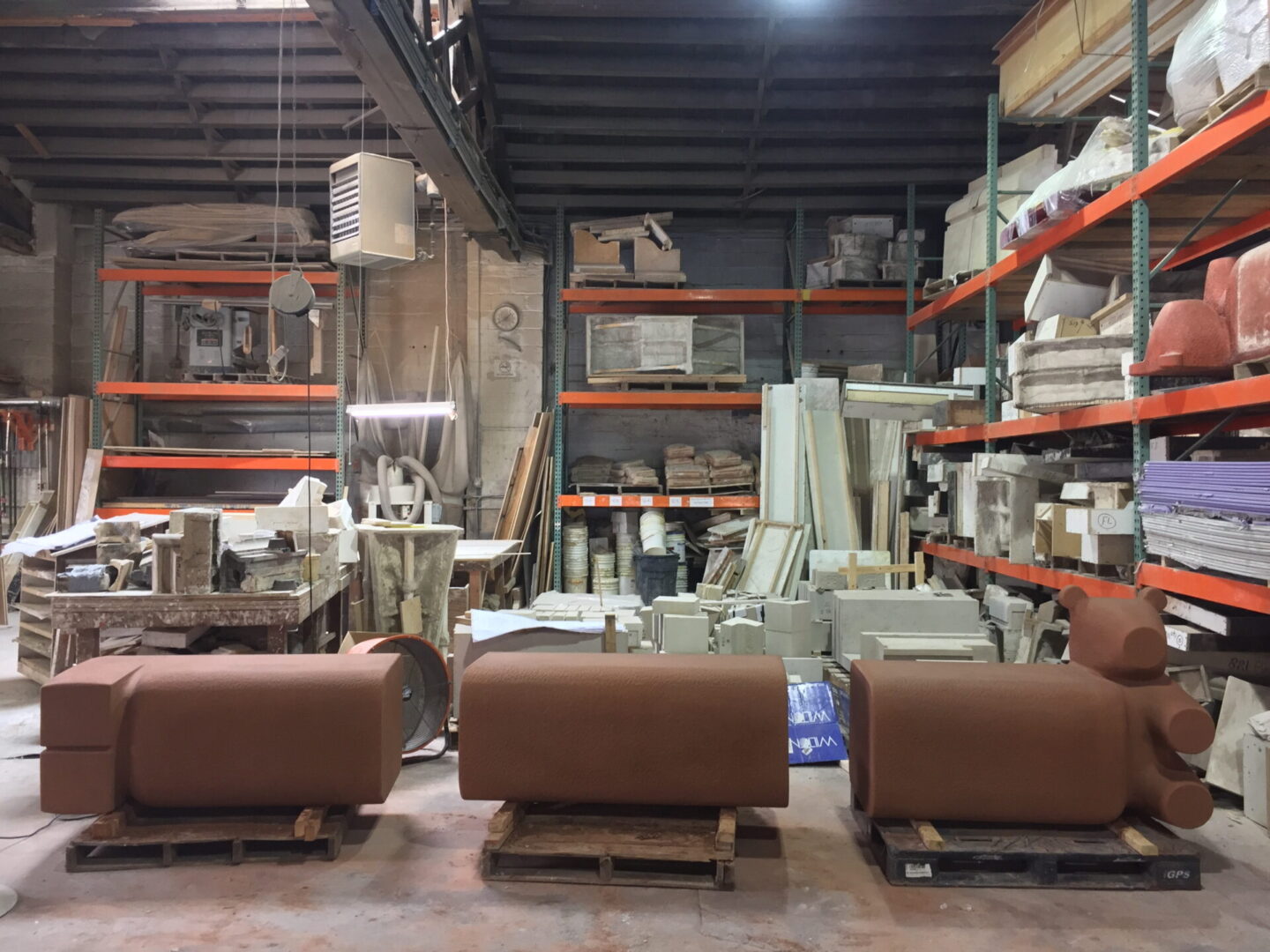 A warehouse filled with lots of shelves and some brown couches.