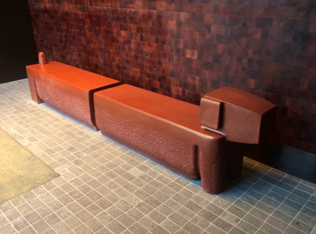 A red bench sitting in front of a wall.