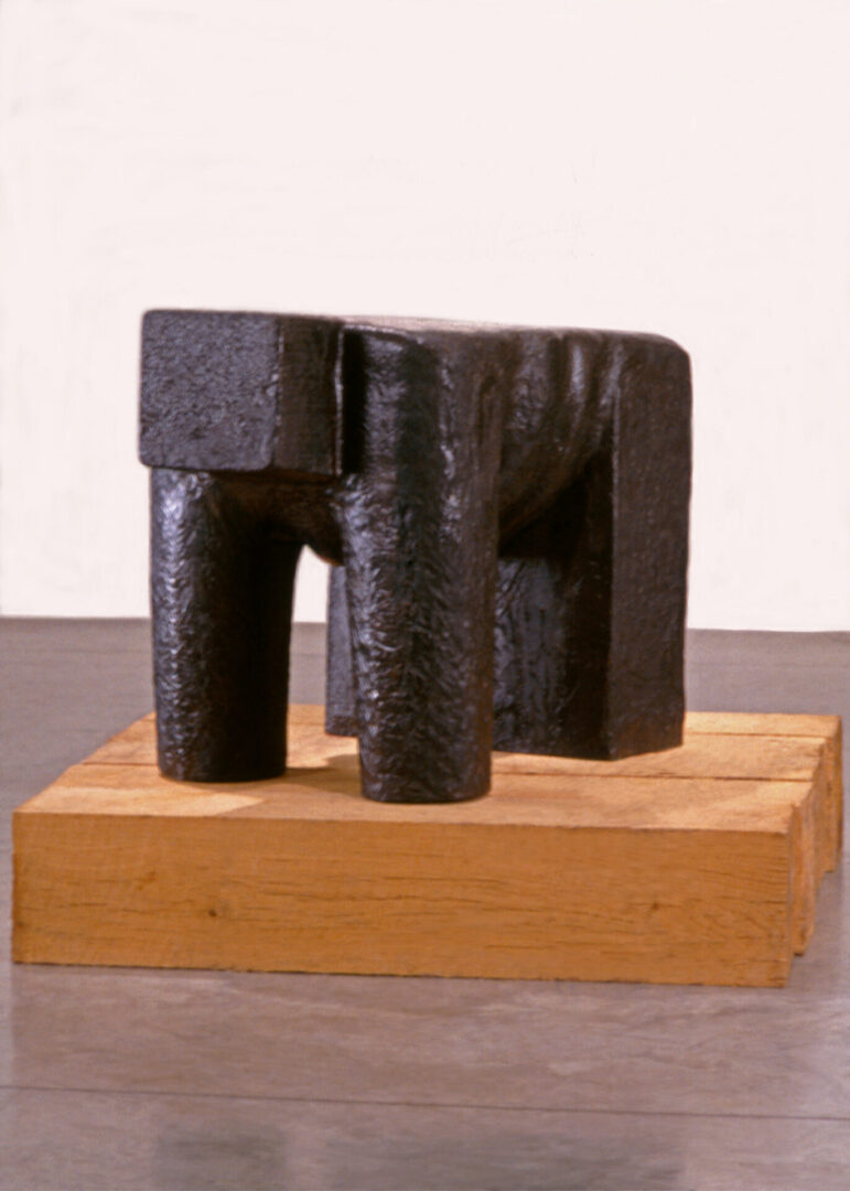 A black sculpture sitting on top of a wooden block.