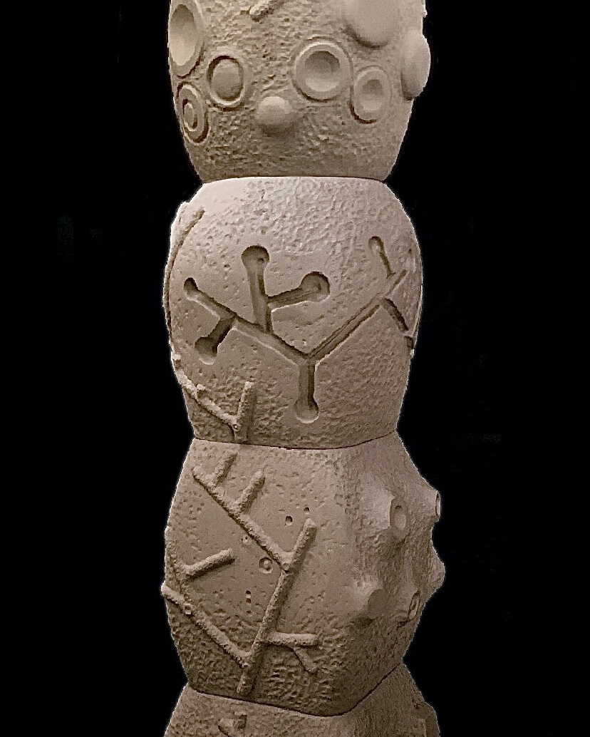 A tall ceramic sculpture of some kind with various designs.