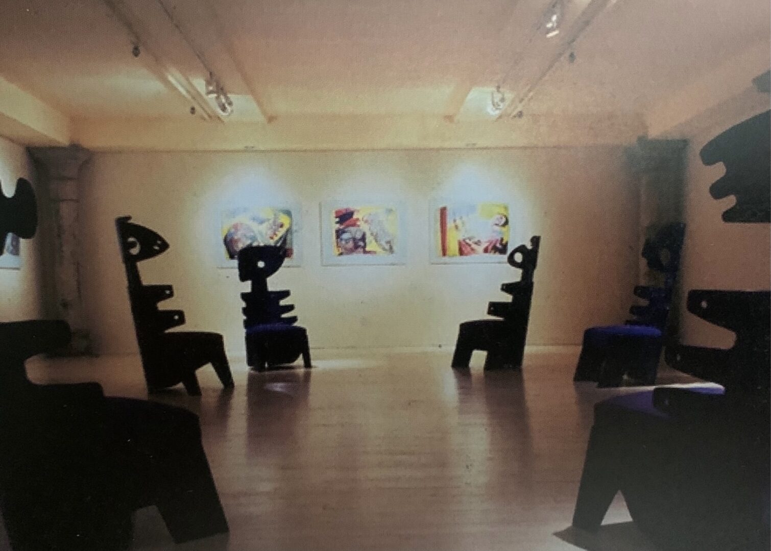 A room with several chairs and paintings on the wall.