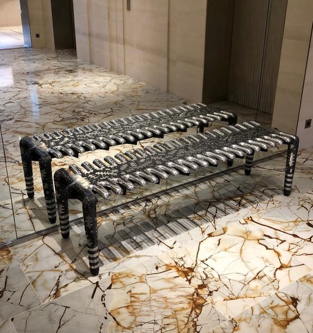 A pair of benches made out of pipes and metal.