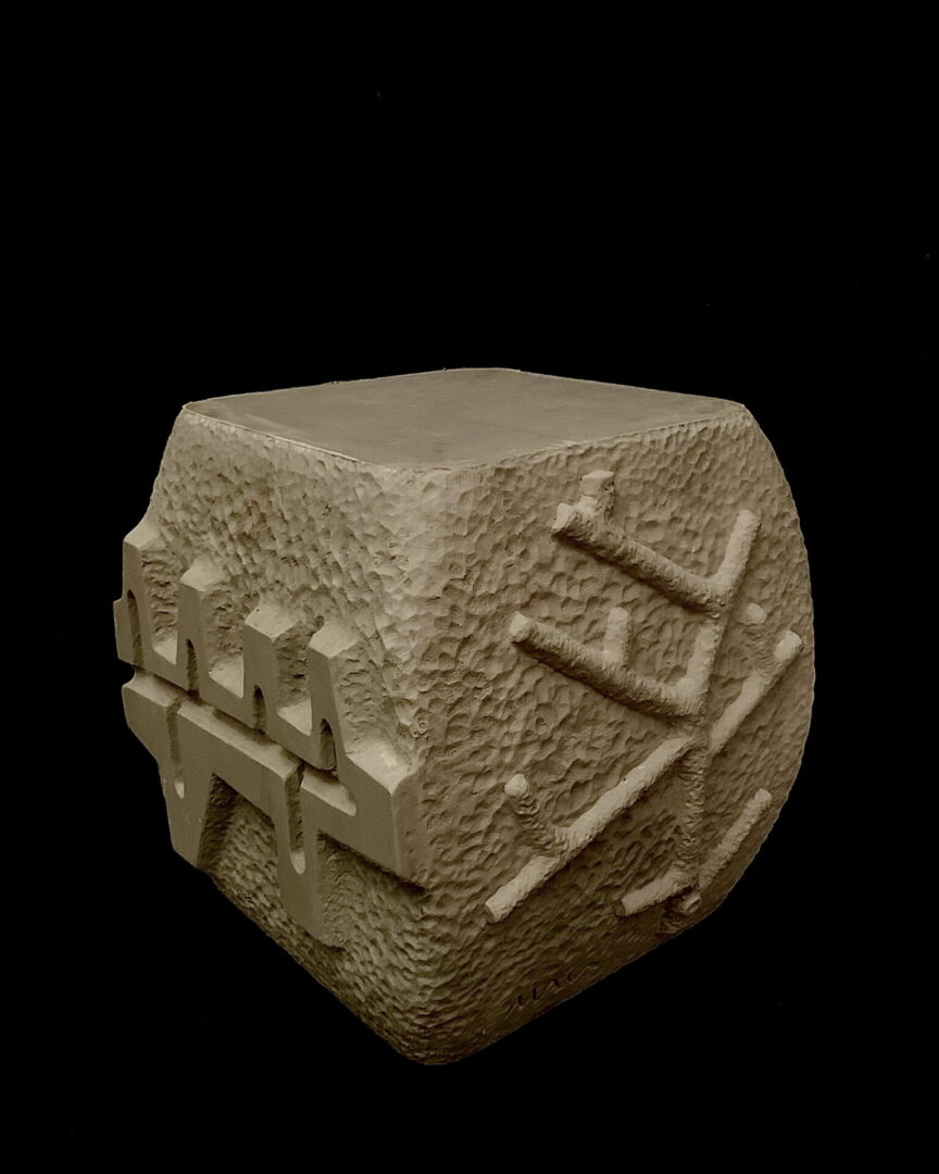 A stone cube with some type of writing on it