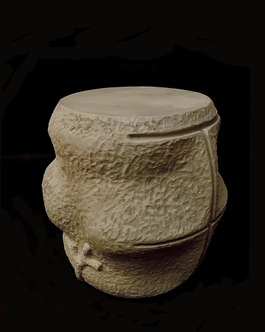 A stone stool with a handle on top of it.